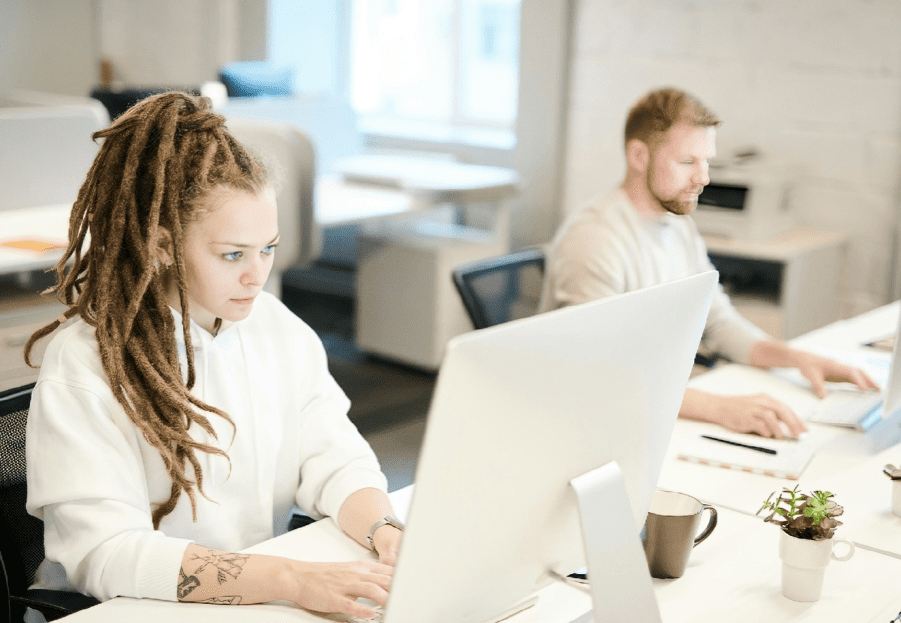 A woman and man sitting at a table with laptops.