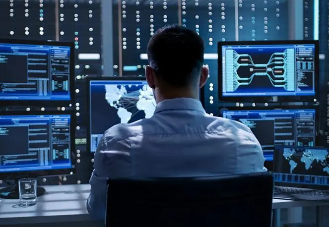 A man sitting in front of multiple computer screens.